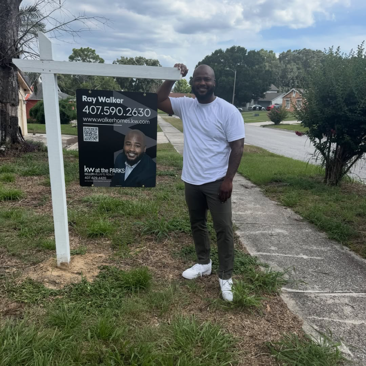 Ray Walker beside his real estate sign